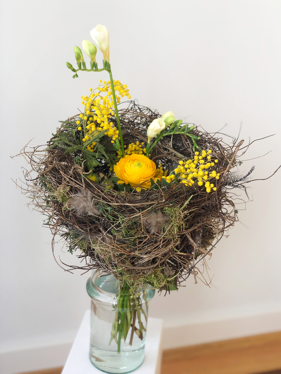 Blumenstrauss im Nest mit Ranunkeln, Mimosen und Freesien