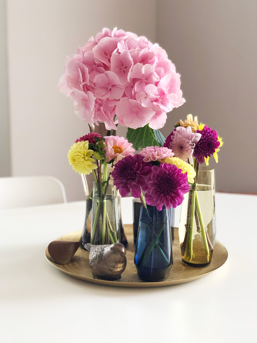 Verschieden Vasen mit Hortensien und Dahlien auf einem goldenen Tablett arrangiert